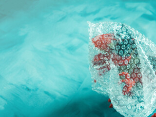 Toy dinosaur in plastic package on turquoise background. Plastic as visible threat, aggressive...