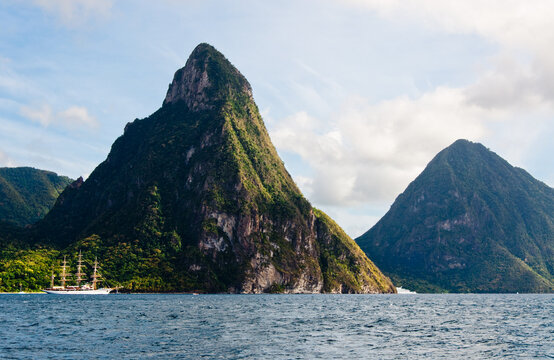 Vacation sailboat with masts near large mountains by caribbean ocean water
