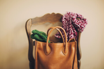 leather bag, wool mittens, and scarf ready on a chair