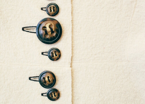 buttons of varying sizes on a white wool sweater