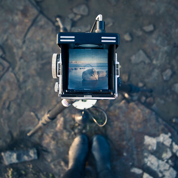 looking down at the viewfinder of a twin lens reflex camera