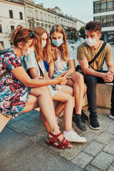 Fototapeta premium Family spending time together sitting in the city center. Girls wearing the face masks to avoid virus infection and to prevent the spread of disease in time of coronavirus