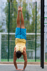 Muscular man doing a handstand outdoors