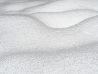 Wavy snow surface background, bumpy land covered by newly-fallen snow closeup, selective focus,...