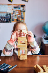 Little girl preschooler playing with wooden blocks toy building a tower. Concept of building a house