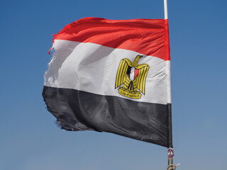 Egyptian flag flapping in the wind against blue sky