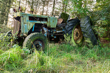 Fototapeta na wymiar A rusty old disused tractor in woodland