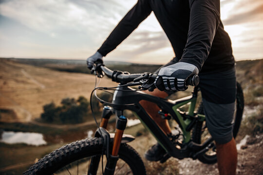 Crop cyclist riding bike in mountains