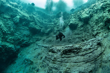 Diver's immersion in a natural funnel with clear water. The water is only 6 degrees, the...