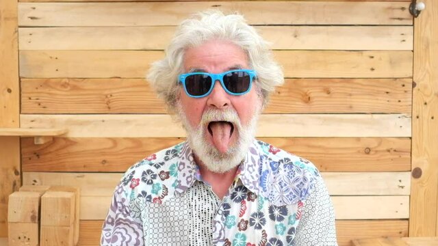 Handsome senior aged alternative diverse caucasian mature man in front of the camera in funny and nice portrait - cheerful retired people have fun and enjoy life