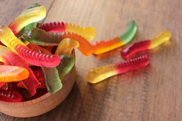 Halloween gummy worms in a bowl. Colorful jelly worms shaped candies. Top view, selective focus
