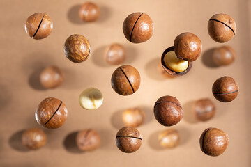 Macadamia on brown background. Falling nuts. Shallow DOF, top view.