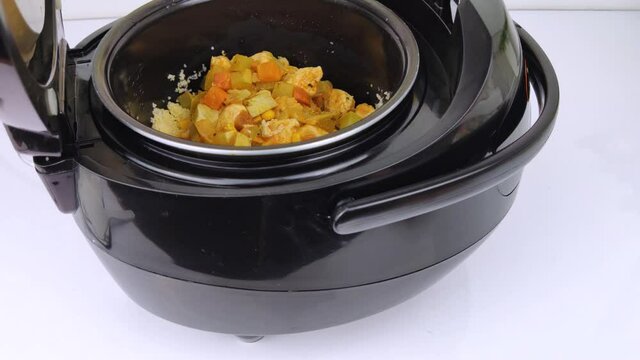 Macro Video of a multicooker. The man opens the pan and mixes the dish. Steam can be seen from the cooked food. The concept of cooking automation and ease in the kitchen.