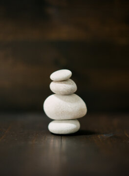 White Greece beach rocks balancing on a dark wood background