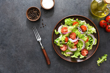 Vegetable salad with tomatoes, red onions and sauce on a black background.