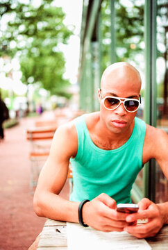 Stylish man at a cafe using his smartphone while ignoring his menu