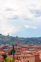 Aerial panoramic view of old Bologna city. It is saw Asinelli tower or torre, San Petronio church or basilica and San Luca church or basilica. Cloudy and sunset sky and bolognese hills in background