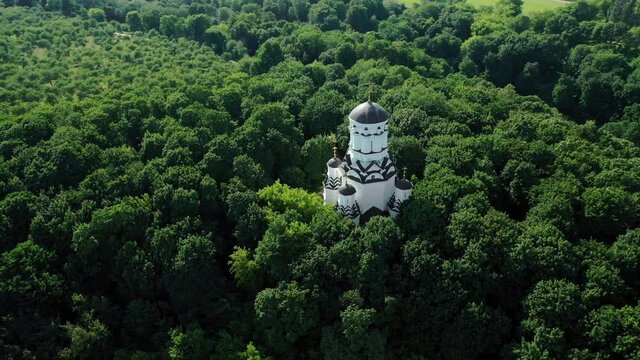 White little church around green dense forest. Aerial view from drone.