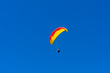 Paraglider in the blue sky. The sportsman flying on a paraglider.