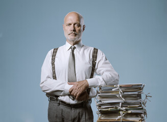 Confident businessman posing with a pile of paperwork