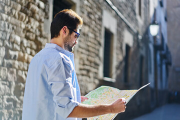 Pensive young man checking direction on map