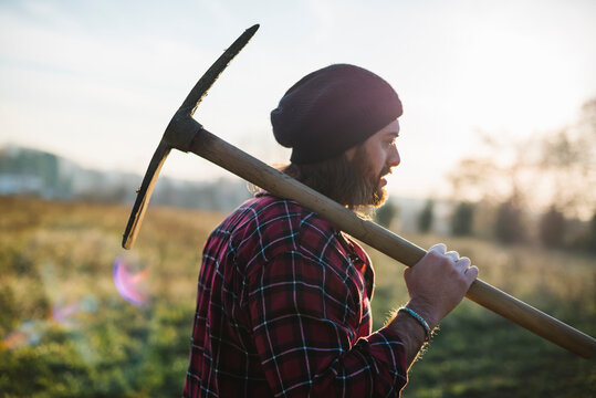 Young lumberjack walking with pickaxe on the shoulder