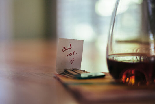 Call Me written on a match book next to a glass of alcohol