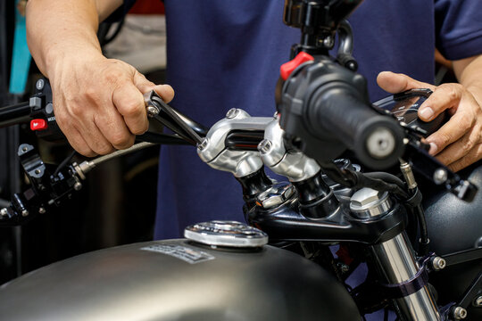 mechanic using Hex Key Wrench working on motorcycle at motorbike garage , concept of motorcycle maintenance and repair . selective focus