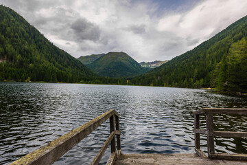 mountain lake with wooden jetty and rainclouds