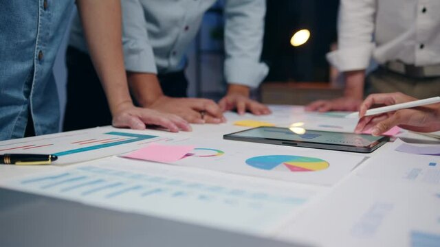 Millennial Asia businessmen and businesswomen meeting brainstorming ideas about new paperwork project colleagues working together planning success strategy enjoy teamwork in small modern night office.