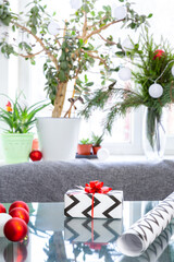 Christmas gift, wrapping paper, Christmas balls on a glass table against the background of a window . New Year, xmas.