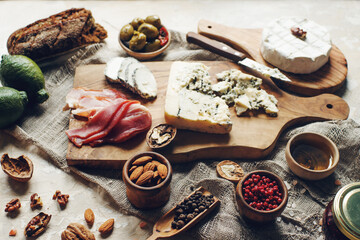 Set of cheese, hamon, honey, green olives, nuts and spices on rustic wooden board