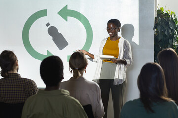 Portrait of young African-American woman giving speech on recycling and waste management during eco...