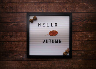 The letter board lies on a wooden table and on it the inscription Hello Autumn. 