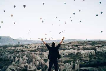 Foto op Plexiglas Kantoor Anonieme gemotiveerde man die zijn armen opheft tegen heteluchtballonnen