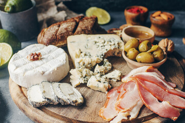 Set of cheese, hamon, honey, green olives, nuts and spices on rustic wooden board