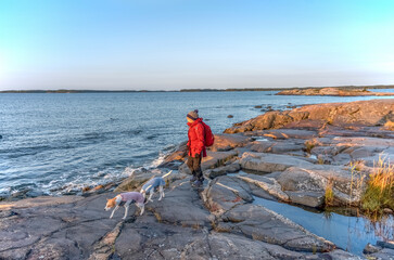 Fototapeta premium Woman walking on rocky sea beach