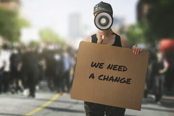 public protest and riots in the city streets. woman with megaphon and cardboard poster in hands on...