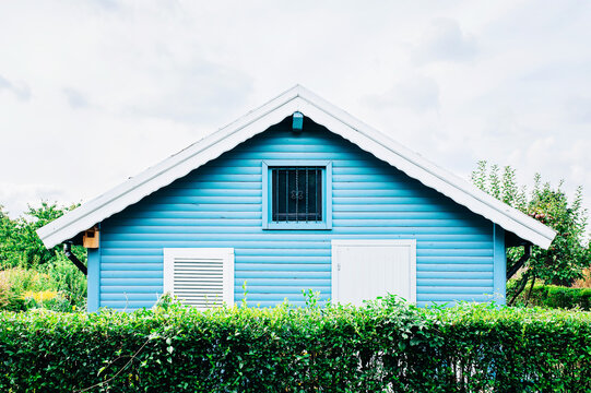 Blue Wooden Summerhouse behind a Hedge