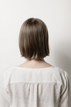 Back view of young woman with short hair over white background.
