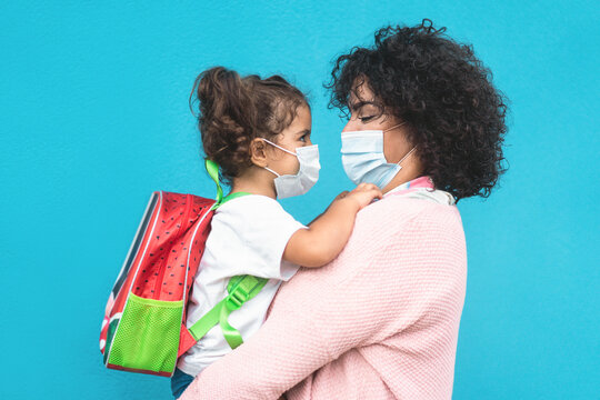 Mother Hugging Her Daughter Going Back To School - Family People Wearing Face Masks - Preschool During Coronavirus Outbreak Concept - Main Focus On Mom Face