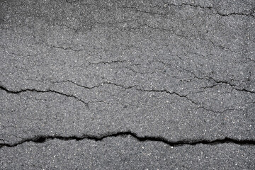 Fototapeta premium cracked asphalt concrete background. damaged road surface caused by torrential rainfall or earthquake disaster.