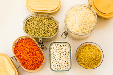 Uncooked dry cereal food group in glass containers on white,above view
