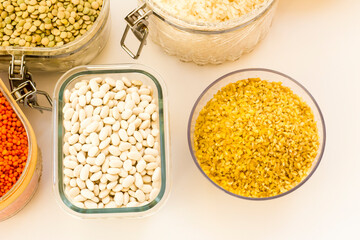 Uncooked dry cereal food group in glass containers on white,above view