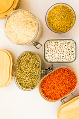 Uncooked dry cereal food group in glass containers on white,above view