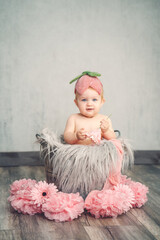 Fototapeta premium Baby Mädchen mit Blumenmütze rosa sitzt in Zinkeimer mit rosa Dekor Var. 3