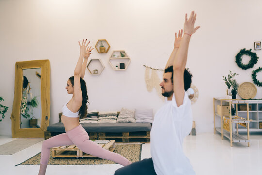 Young man and woman practicing yoga in modern apartment