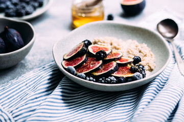 Oatmeal with figs, wild berries and honey in a plate. 