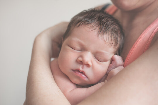 Adorable newborn baby girl sleeping in her mother's arm