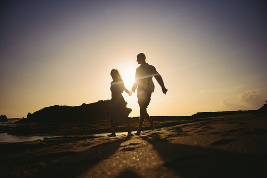 Young couple silhouette on the beach at sunset